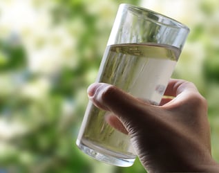 hand holding glass of brownish water