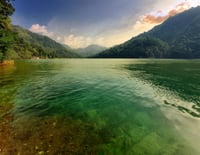 Lake with green tinge, forested mountains in background