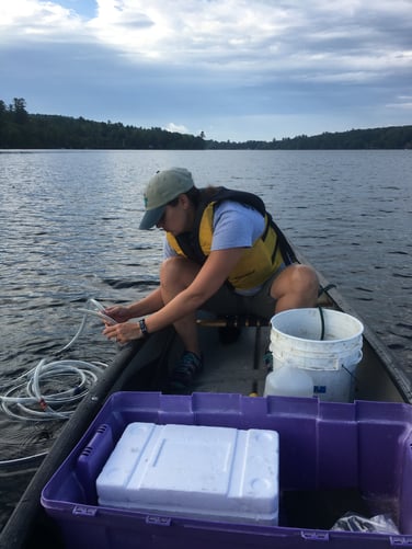 person in boat on lake taking a water sample