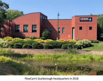 Brick building surrounded by plants and pond