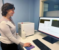 Woman standing at lab bench with FlowCam and monitor