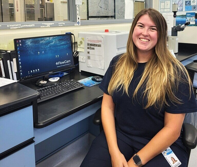 Woman at lab bench with computer and FlowCam