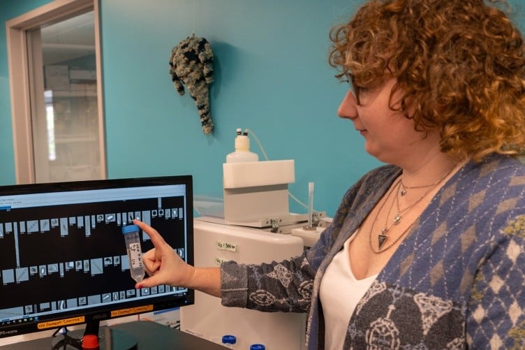 Scientist looking at test tube and screen with phytoplankton images