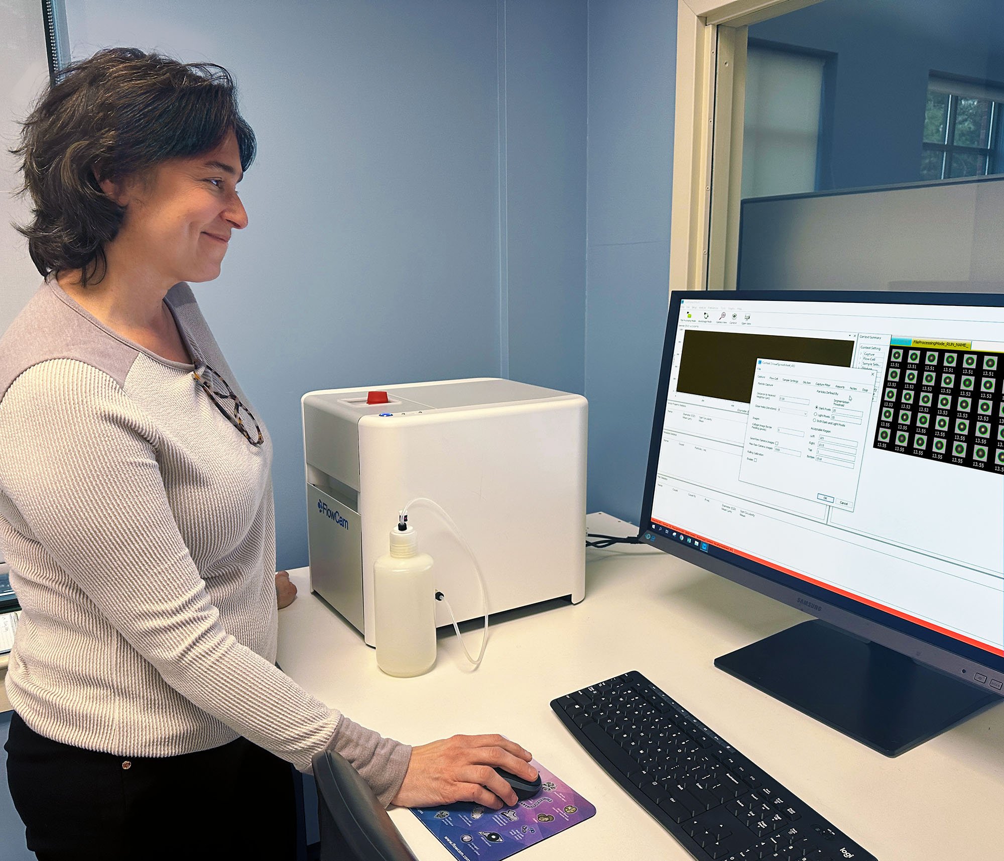 scientist at lab bench using FlowCam with monitor